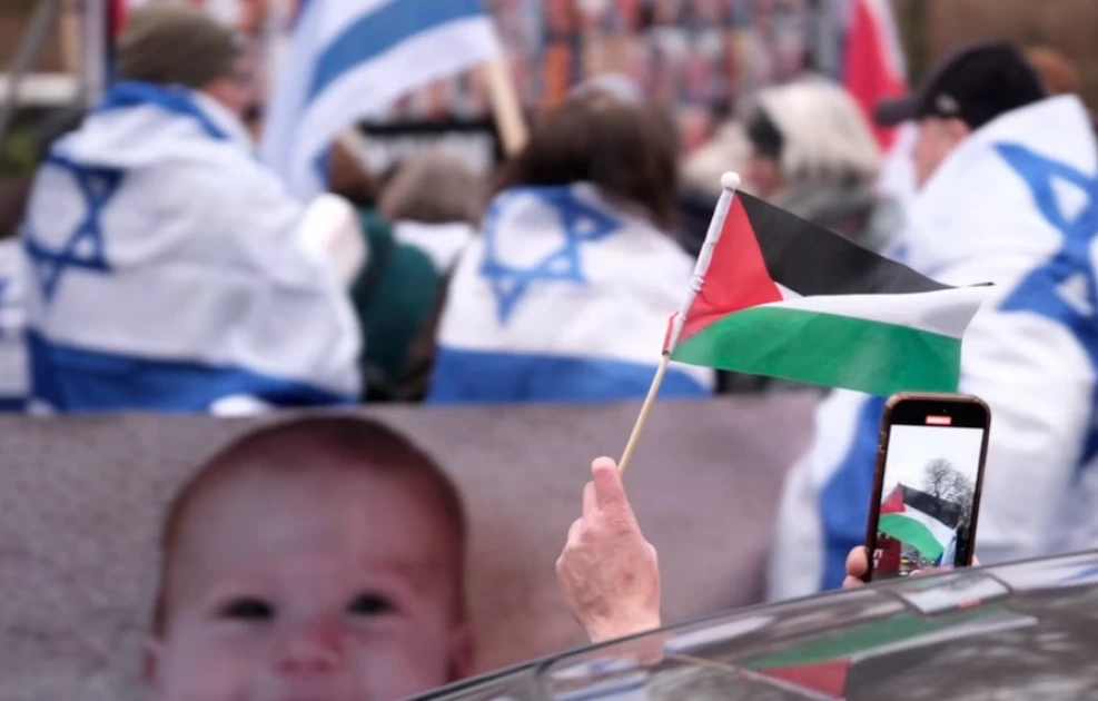 A person waves a Palestinian flag while passing a pro-Israel protest outside the International Court of Justice in The Hague, Netherlands, Jan. 12, 2024.