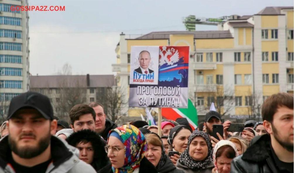 People take part in an election event in the Chechen capital Grozny, Russia. The slogan next to Putin on the poster reads: 