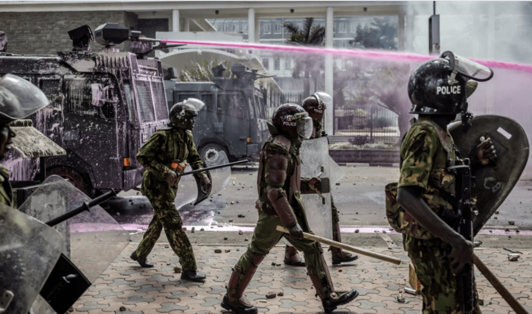 Kenya Police officers move in formation next to water cannon trucks as they clash with protesters during a nationwide strike to protest against tax hikes and the Finance Bill 2024 in downtown Nairobi, on June 25, 2024. (Photo by LUIS TATO / AFP)